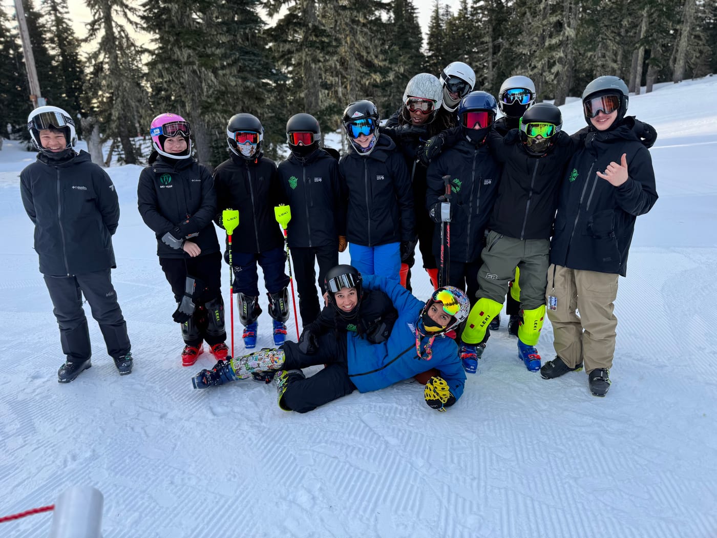 The full IBW ski race team on a groomed pitch at the end of a training day, two of them lying in the snow at the front